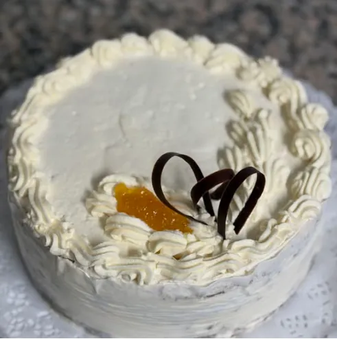 Torta Mon Rêve decorada con crema chantilly, durazno y chocolate